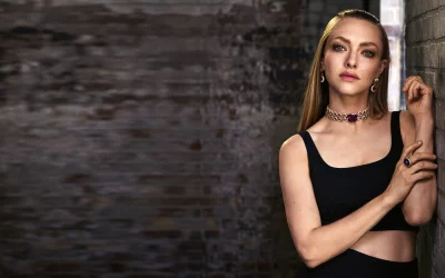 Glamorous Woman in Black Top with Statement Gemstone Jewelry Against Textured Brick Wall image