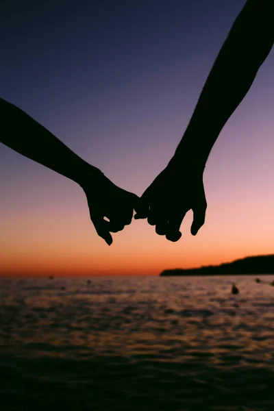 Couple's Pinky Promise Against Breathtaking Sunset Over Serene Ocean Horizon image
