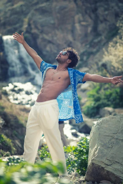 Joyful Man with Outstretched Arms at Waterfall