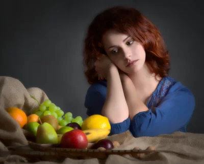 Pensive Young Woman with Red Hair in Blue Dress Beside Fruit Still Life image