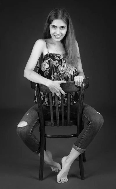 Smiling Young Woman Posing on Wooden Chair in Ripped Jeans image