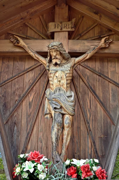 Carved Wooden Jesus Christ Crucifix Adorned with INRI Banner and Floral Arrangements image