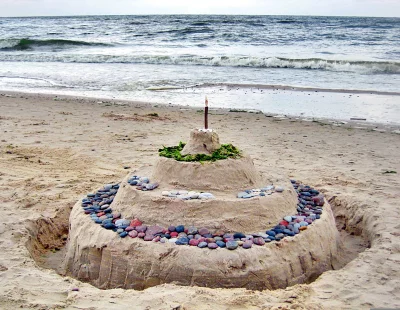 Intricate Sandcastle Creation Decorated with Pebbles and Seaweed on a Coastal Beach image