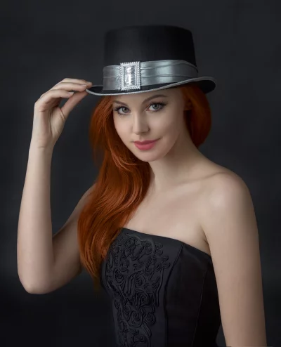 Confident Red-Haired Woman Adjusting Ornate Top Hat in Studio Portrait image