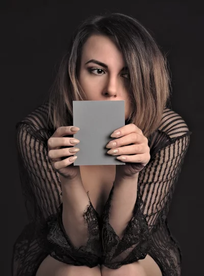 Intriguing woman in black lace holding blank grey card for design element image