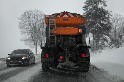 Orange Road Salt Spreader Truck Actively Working on Snowy Winter Highway image