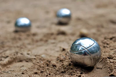 Close-up of Shiny Metallic Pétanque Boules Resting on Sandy Ground for Outdoor Game image
