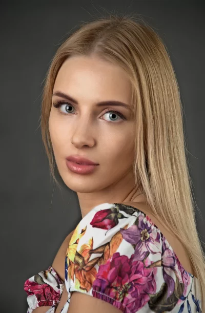 Captivating Blonde Woman in Floral Blouse with Expressive Blue Eyes image
