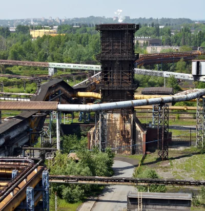 Aging Industrial Facility: Rusty Steel, Towering Structures, Lush Green Surroundings image