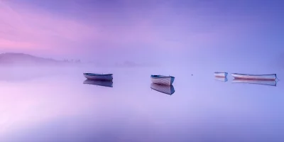 Ethereal Morning Mist Over Still Lake with Wooden Boats and Pastel Sky image