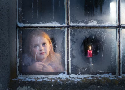 Little Girl Gazing Through Frosty Window at Winter Candle Light image