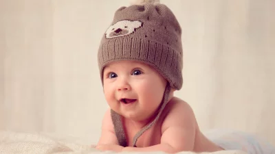 Delighted Infant in Bear Beanie Lying Prone, Smiling Upwards image