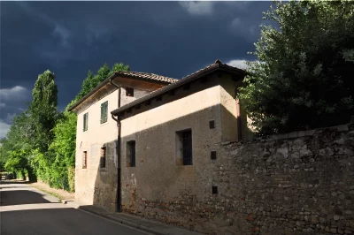Historic European Stone House Under Dramatic Sky with Sunlit Facade image