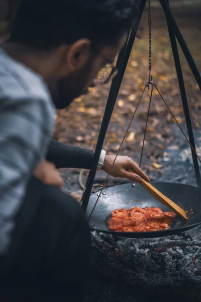 Man Cooking Sliced Vegetables Over an Open Fire Outdoors