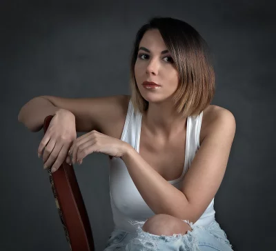 Confident Young Woman in Casual White Tank Top and Ripped Jeans Posing image