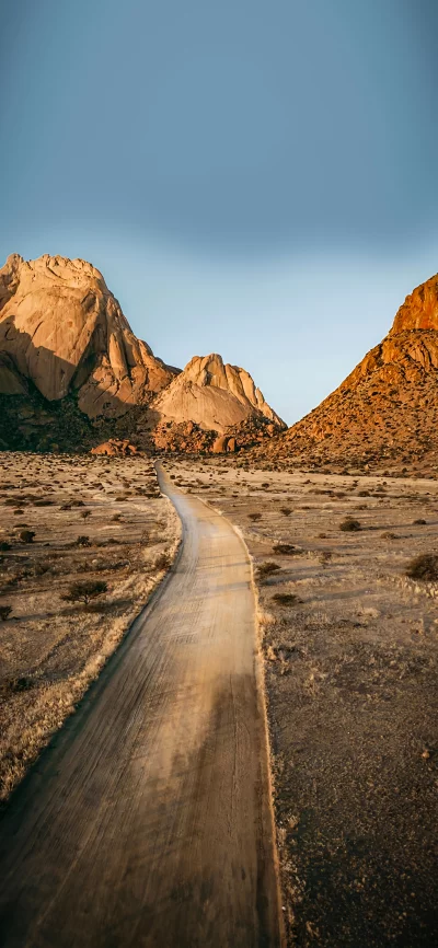 Winding Dirt Road Through Golden Hour Desert Mountains Under a Clear Sky image