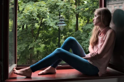 Pensive Young Woman Gazing Out Window at Lush Green Trees image