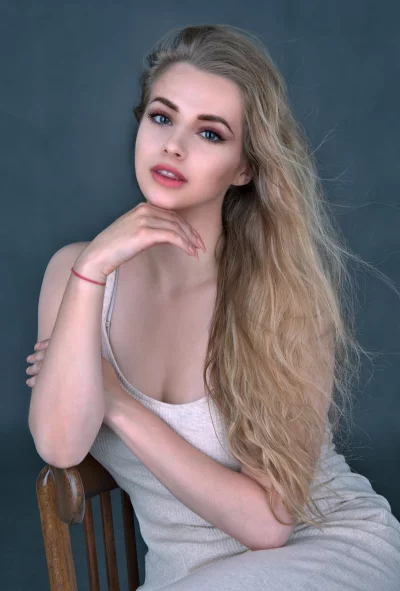 Young Blonde Woman Posing Thoughtfully on Wooden Chair in Studio image