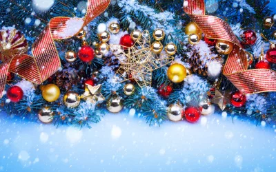 Beautiful snow-covered Christmas tree decorated with golden and red baubles, festive ribbons, and falling snow image