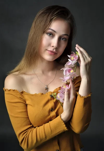 Serene Young Woman with Green Eyes and Pink Orchid Branch image