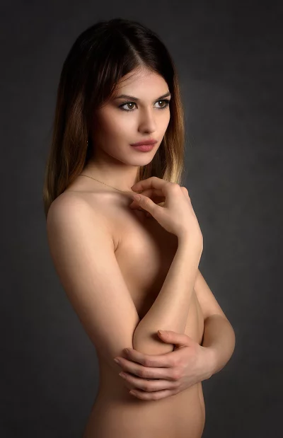 Sensual Portrait of Young Woman Posing Nude with Covered Chest in Studio image