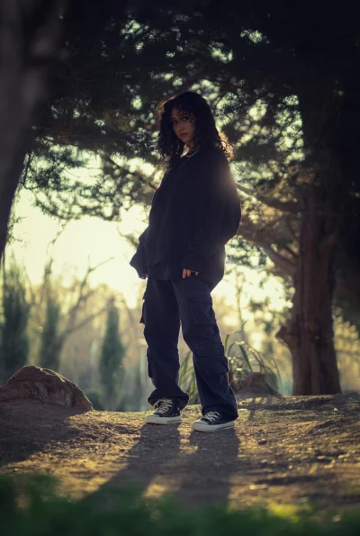 Stylish Young Person in Oversized Hoodie and Cargo Pants Amidst Sunlit Trees