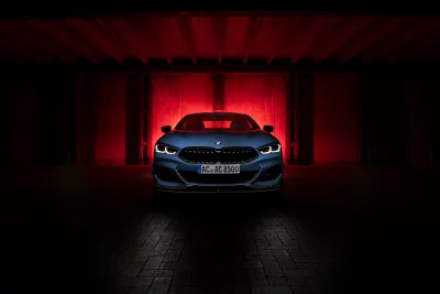 Sleek Blue Luxury Sports Car with Glowing Headlights in Dramatic Red-Lit Garage image