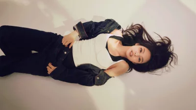 Stylish Young Woman Relaxed in Denim Jacket and White Top on Light Background image