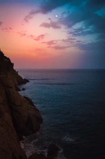 Coastal Sunset with Moon Over Rugged Cliffs and Ocean image