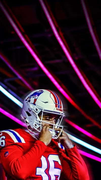 New England Patriots Player Adjusts Helmet Amidst Vibrant Lights