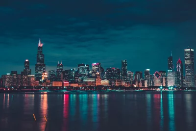 Stunning Illuminated City Skyline at Night with Vibrant Reflections on Calm Water image
