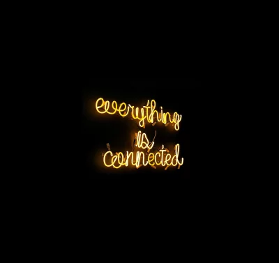 Bright Yellow Neon Sign Displaying 'Everything Is Connected' on Dark Background image