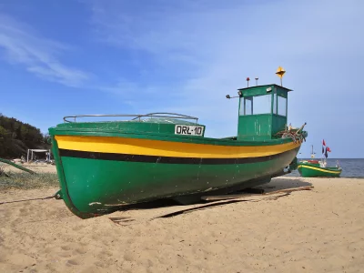 Traditional Green and Yellow Fishing Boats Resting on a Sunny Sandy Beach Shore image