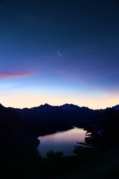 Crescent Moon Reflected in Serene Mountain Lake at Twilight image