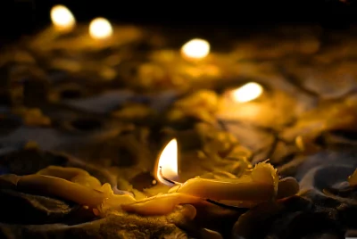 Close-up of Burning Candle with Melted Wax and Warm Bokeh Lights image