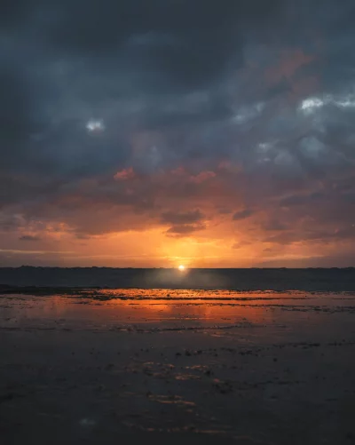 Breathtaking Coastal Sunset with Fiery Sky Reflected on Wet Beach Sand image