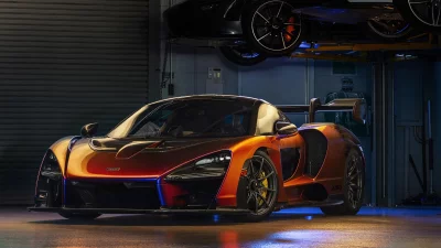 Metallic Orange McLaren Senna Supercar in Dynamic Garage Setting with Blue Lights image