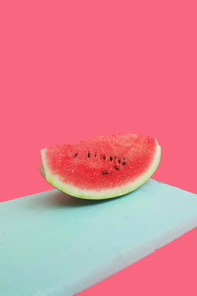 Refreshing Watermelon Slice on Textured Teal Surface Against Pink Background