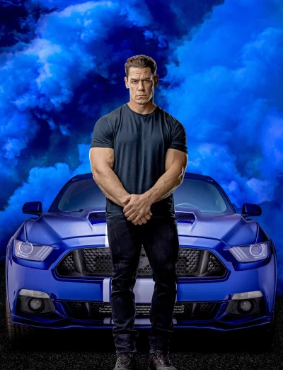 John Cena Posing with Muscular Physique in Front of Blue Sports Car Amidst Smoke image