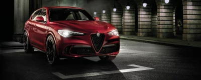 Red Alfa Romeo Stelvio Quadrifoglio SUV on Wet Urban Road at Night image