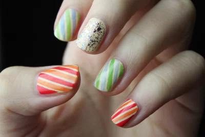 A close-up of a hand with a colorful striped manicure