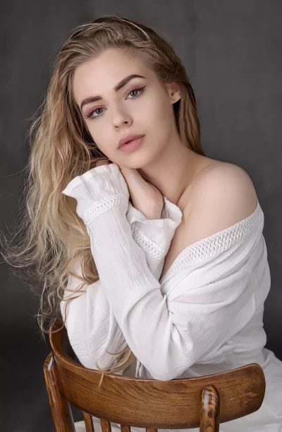 Blonde Woman in White Off-Shoulder Top Posing on Wooden Chair Studio Portrait image