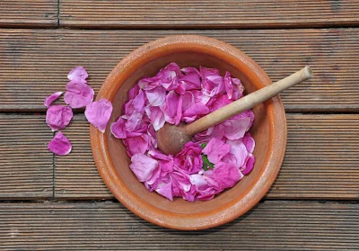 Fresh Pink Rose Petals in Terracotta Bowl with Wooden Pestle on Rustic Wood image