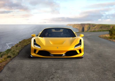 Luxury Yellow Sports Car Parked on Scenic Coastal Road by Ocean Cliffs at Sunset image