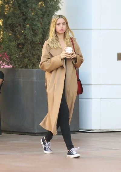 Stylish Woman in Camel Coat and Black Pants Walking Outdoors with Coffee Cup image