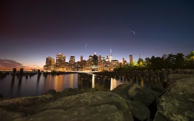 Illuminated Downtown Manhattan Skyline at Twilight with Water Reflections and Light Streaks image