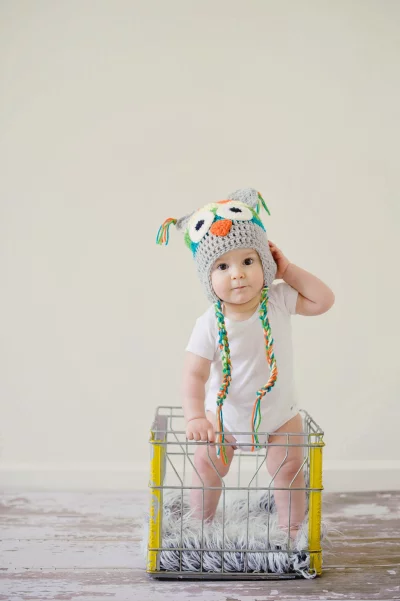 Adorable Baby Posing in Colorful Owl Hat in Rustic Crate image