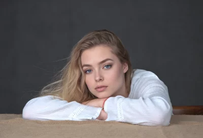 Pensive Young Woman with Blue Eyes and Blonde Hair Resting Arms image