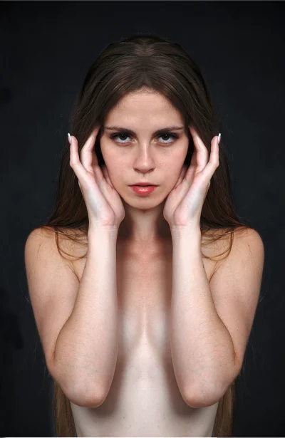 Intense Portrait of Pensive Young Woman with Hands on Temples on Dark Background image
