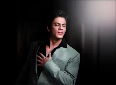 Shahrukh Khan in elegant grey suit with closed eyes and hand on chest feeling deep emotion image